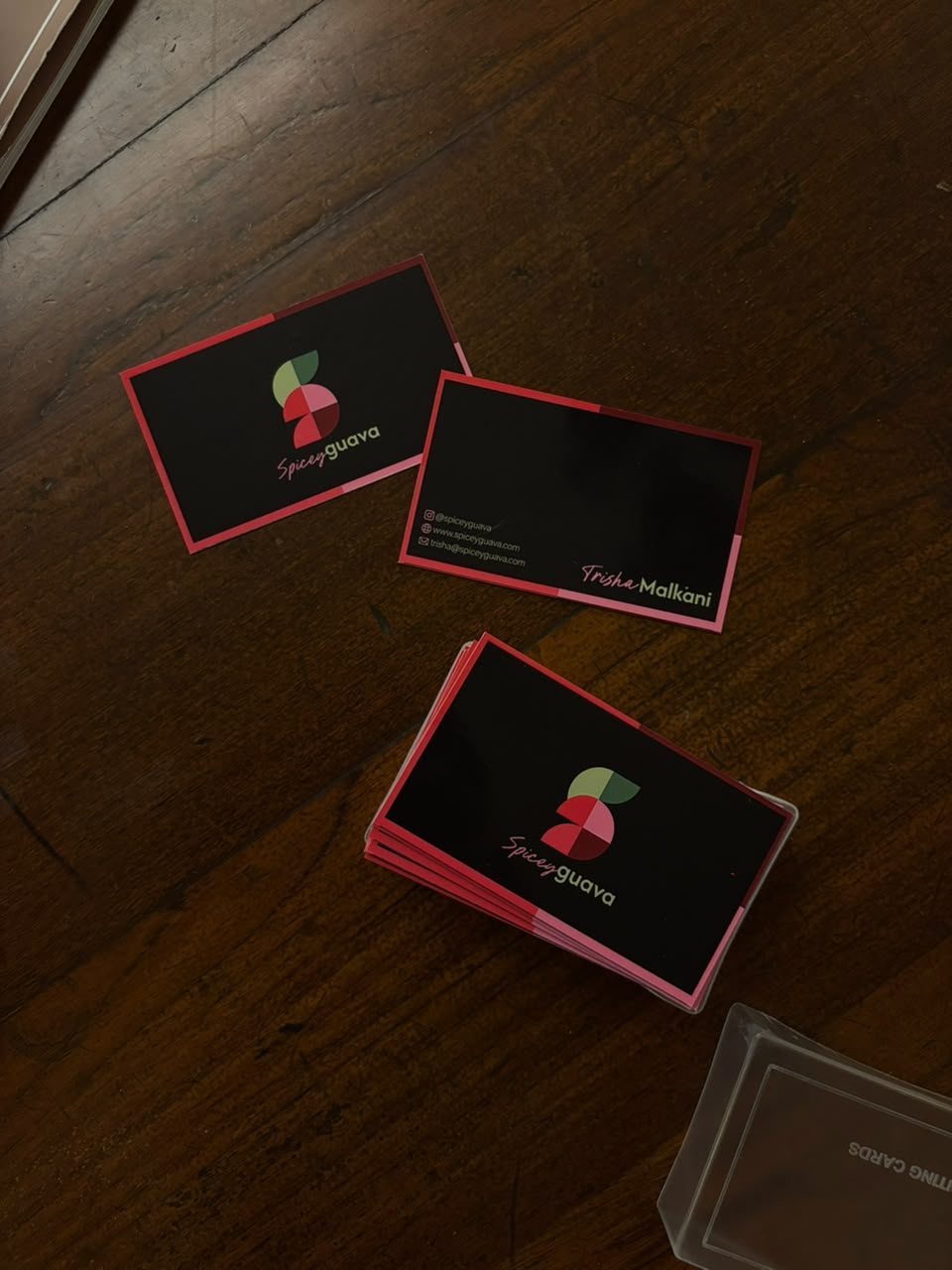 Freshly printed Spicey Guava business cards laid out on a wooden floor